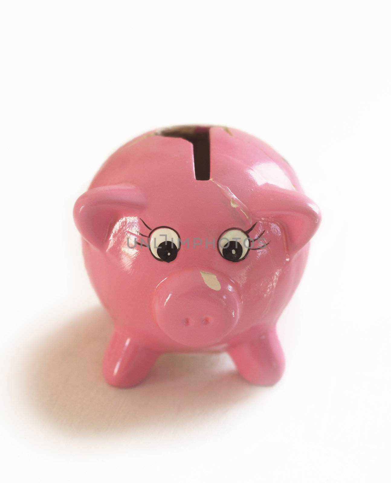 A surprised looking little piggy bank with chips and cracks. Isolated on white
