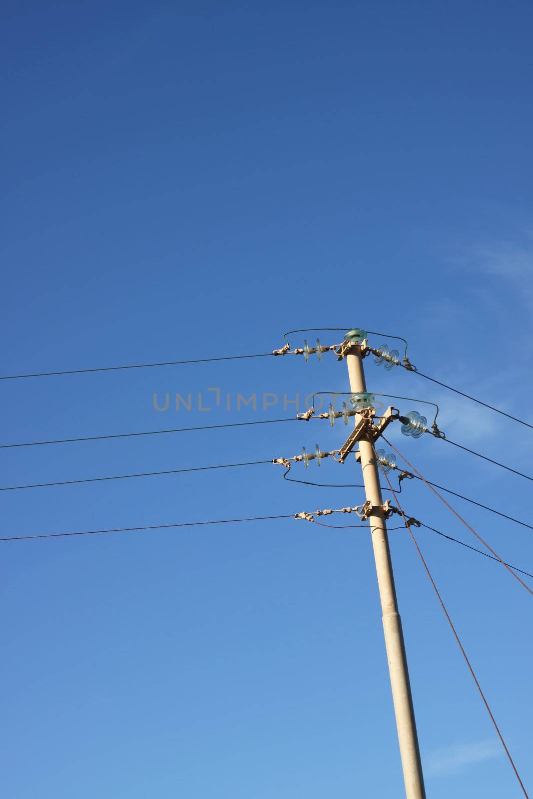 An old telephone pole against a clear blue sky. Space for free text