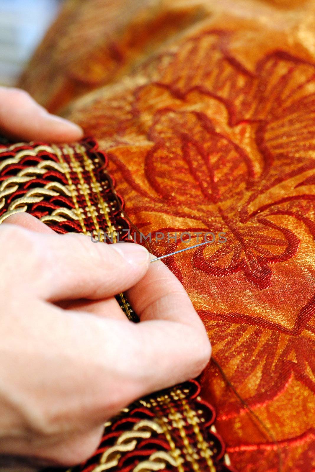 Craftsman hands working on a curtain with a needle