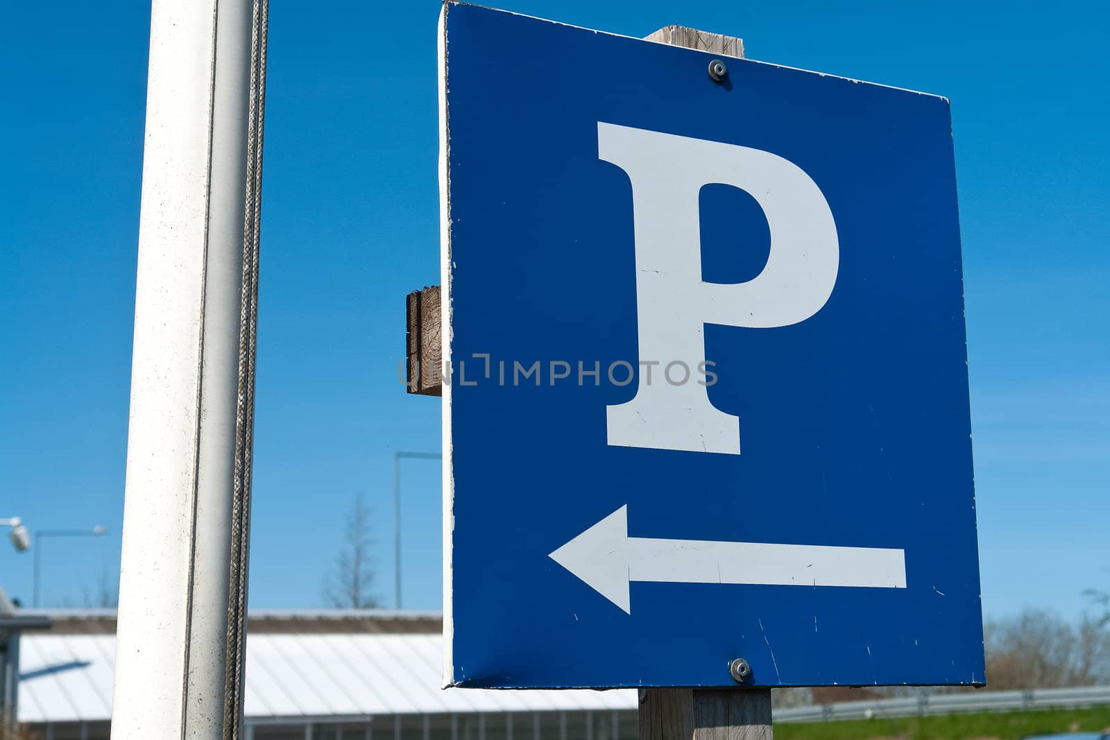 Parking sign with a white 'P' on a blue metal plate with clear blue sky background horizontal