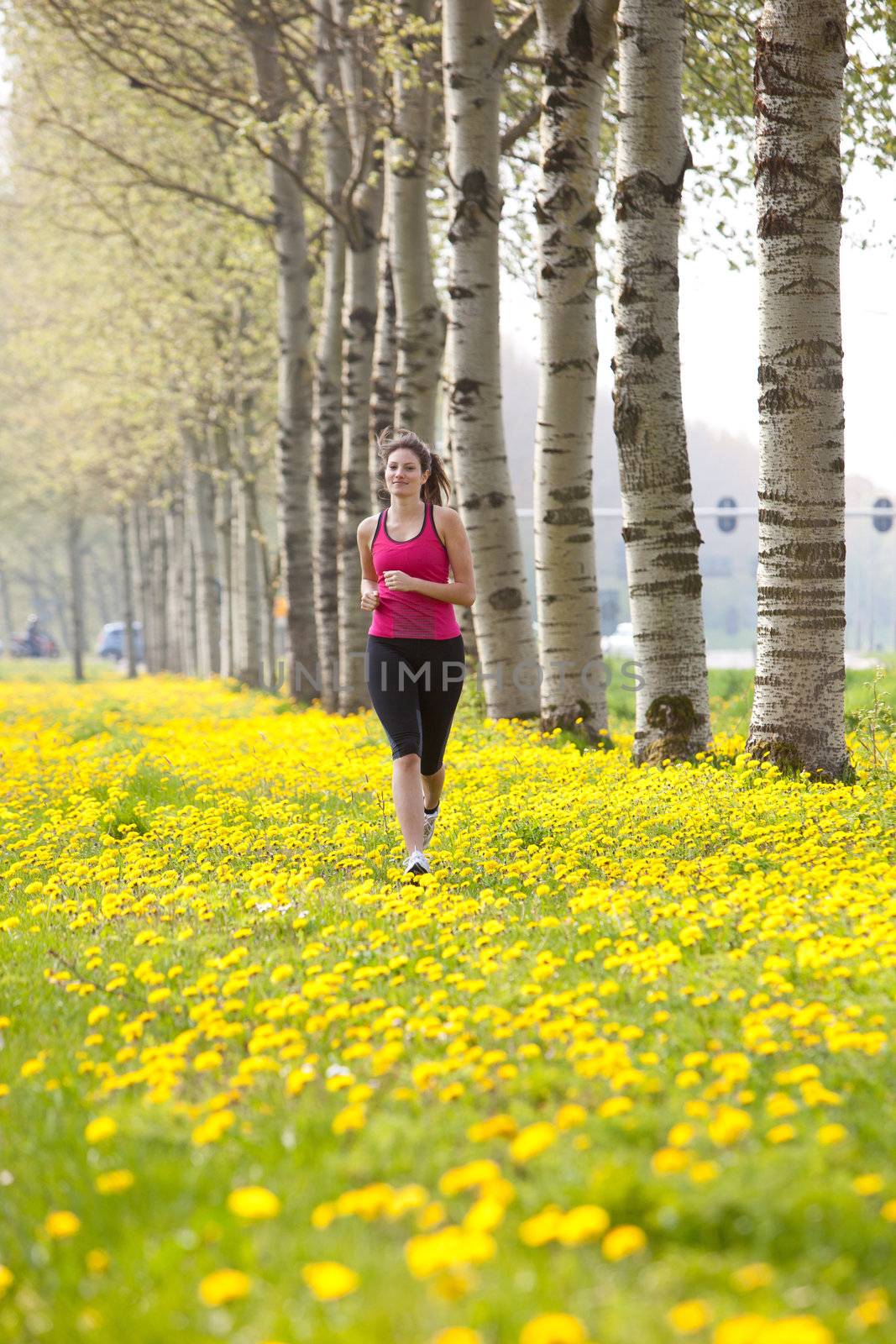 Beautiful young girl running in a field of dandelions