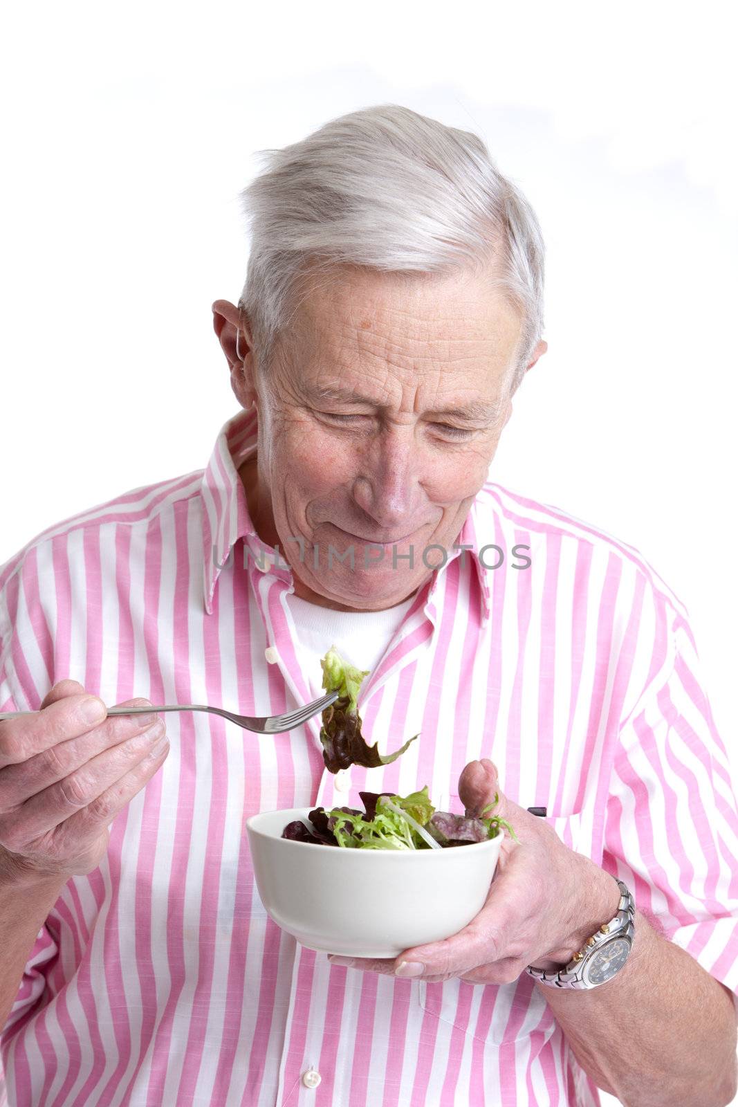 Senior man eating a green salad out of a bowl