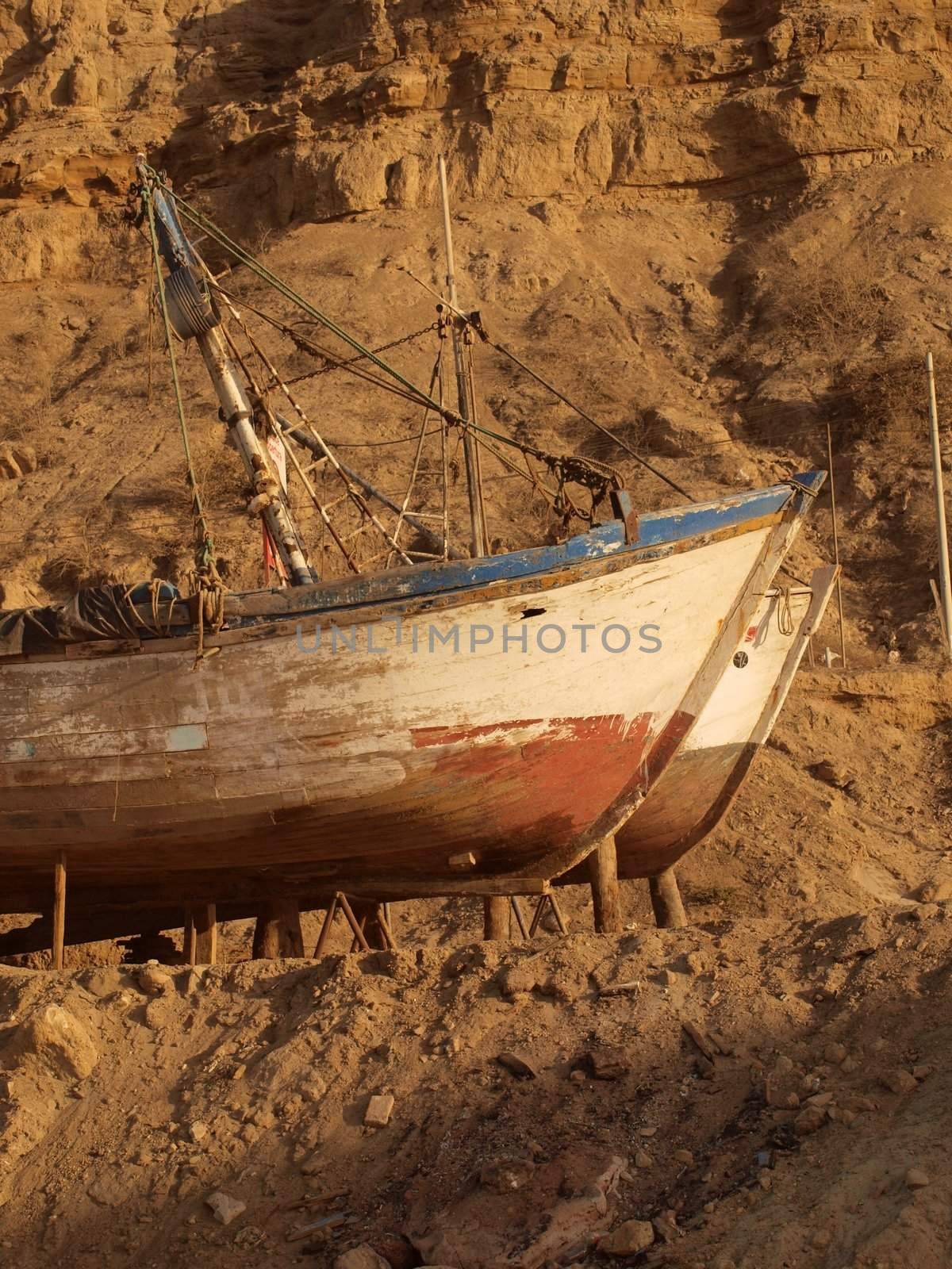 Abandoned fishing boats on rocks by Alminaite