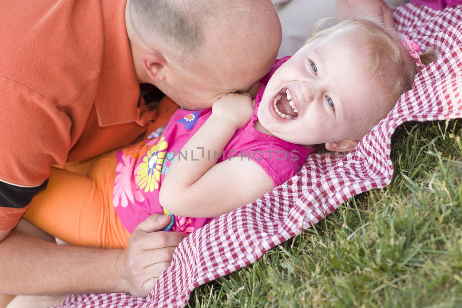 Loving Dad Tickles His Daughter in the Park.