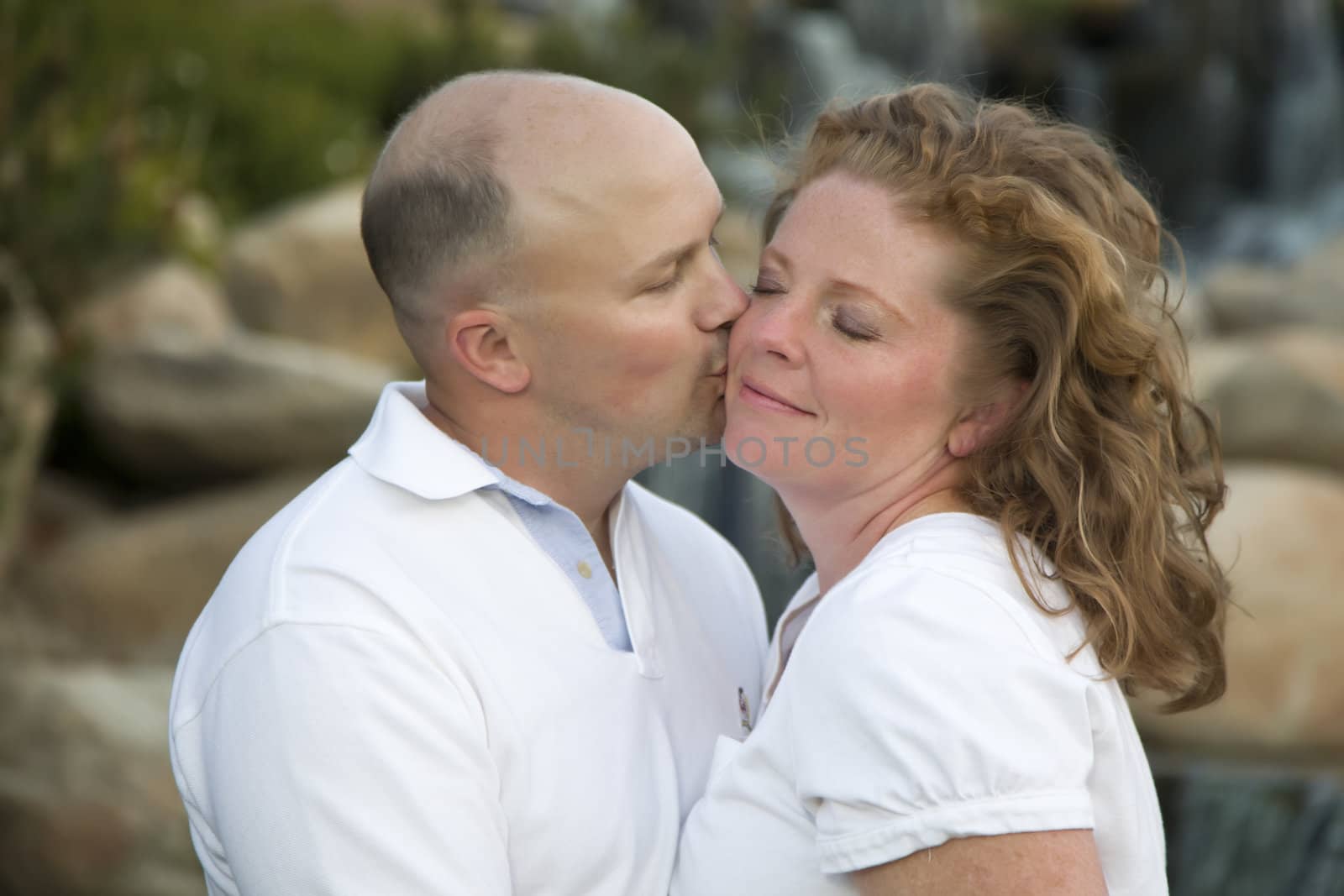 Happy, Attractive, Affectionate Couple Kiss on Cheek in the Park.
