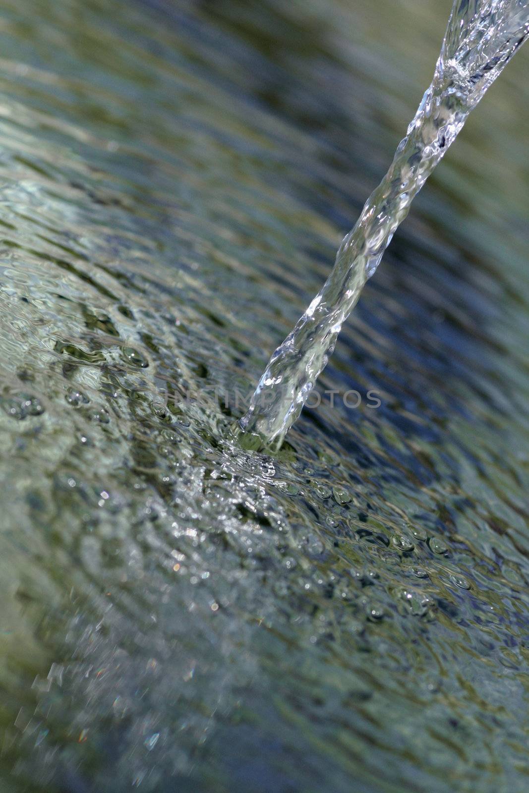 Crystal clear flowing water running into small well.