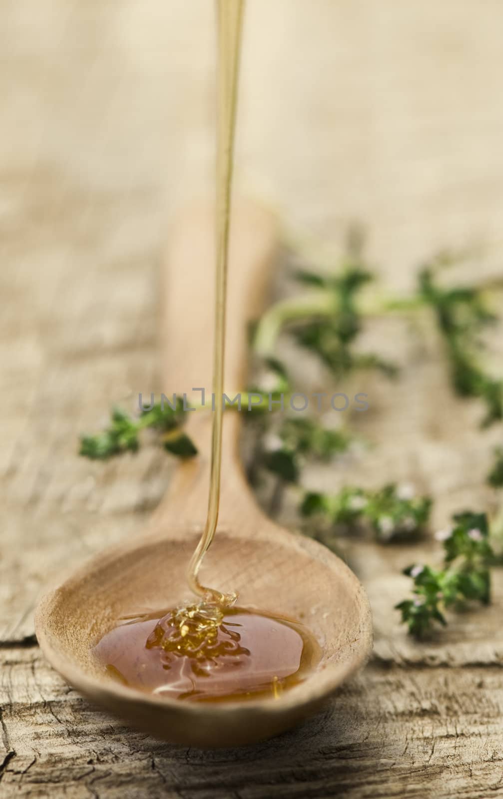 Fresh honey being poured into a rustic wooden spoon