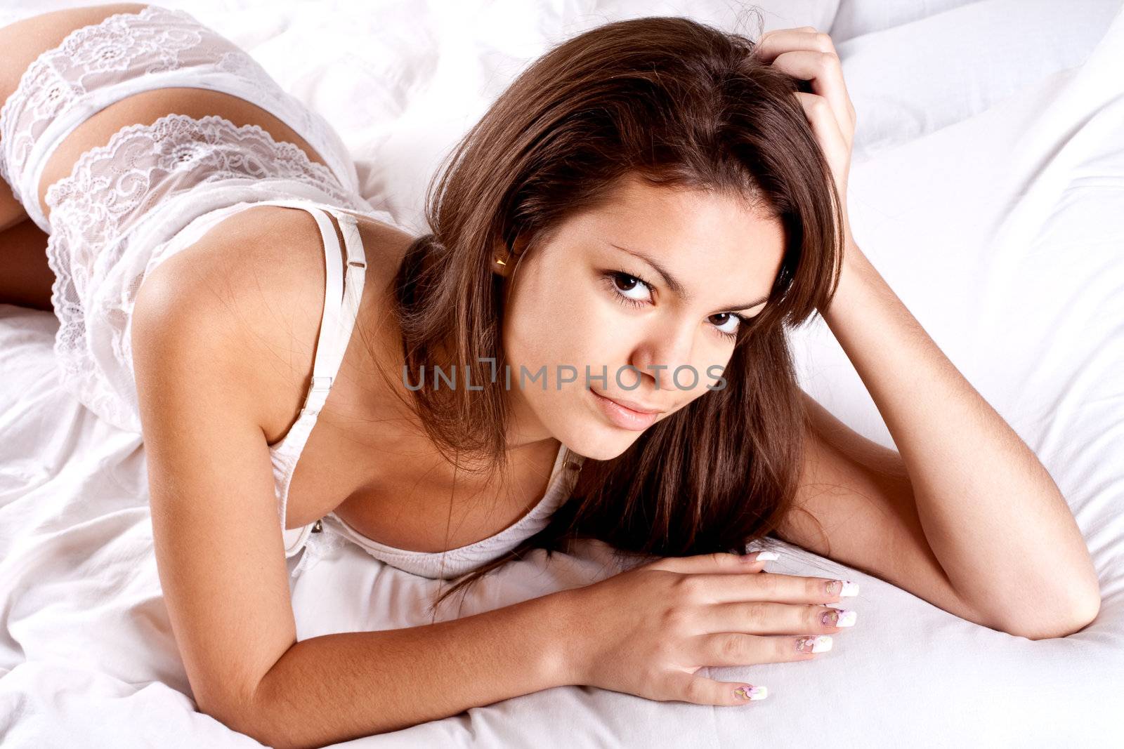 woman lying in bedroom smiling on a white background