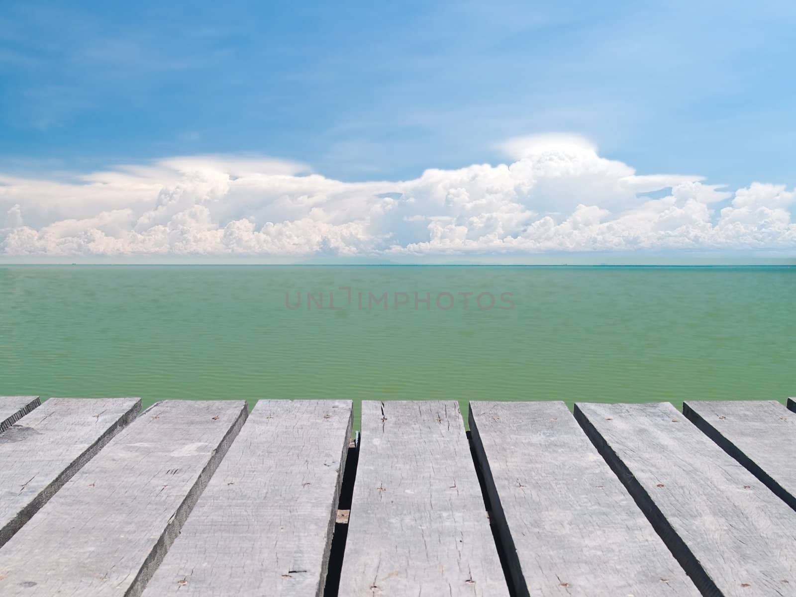 Seaside wooden bridge with beautiful cloudy and emerald color backwater sea