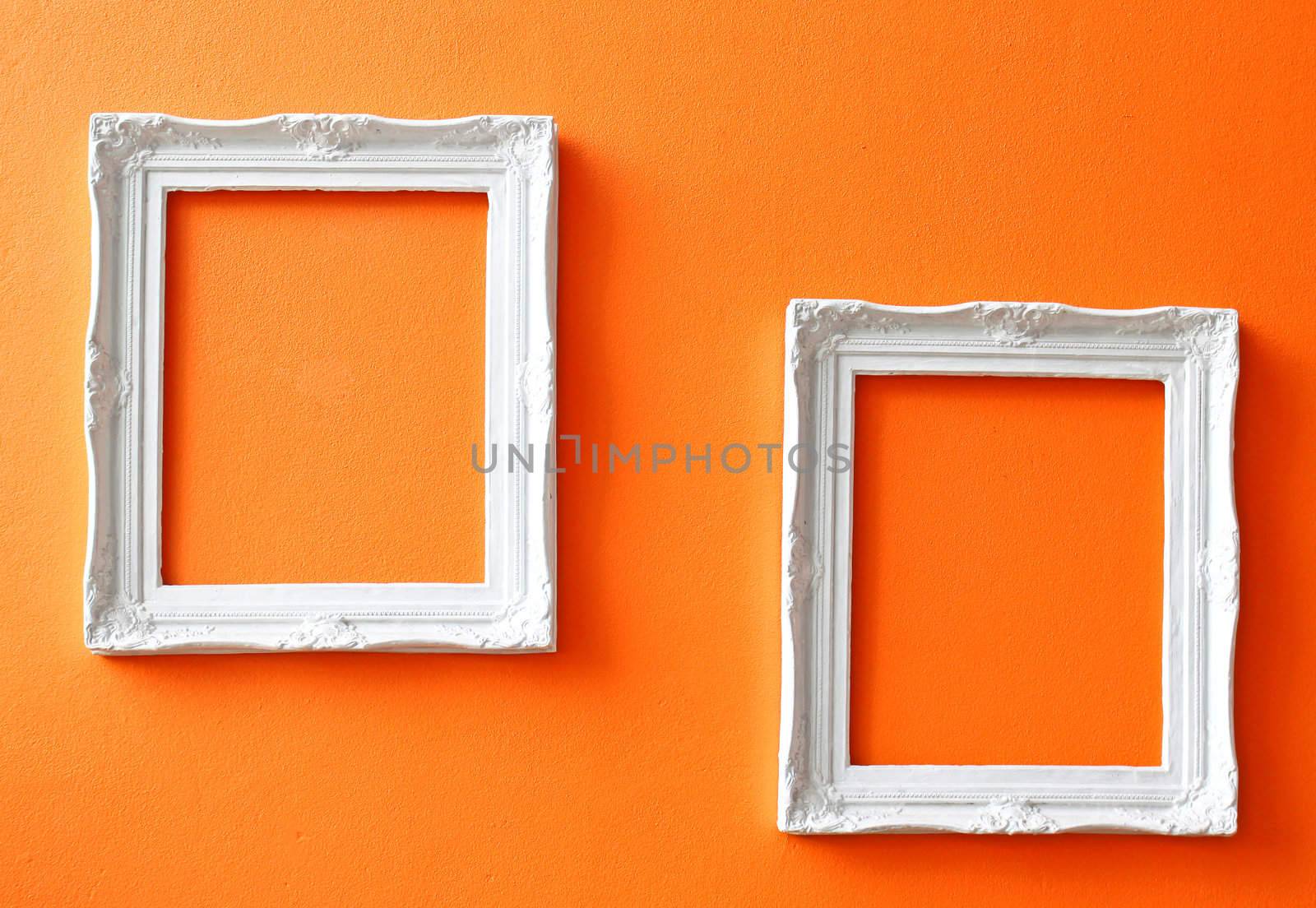 Two white vintage frames on orange wall