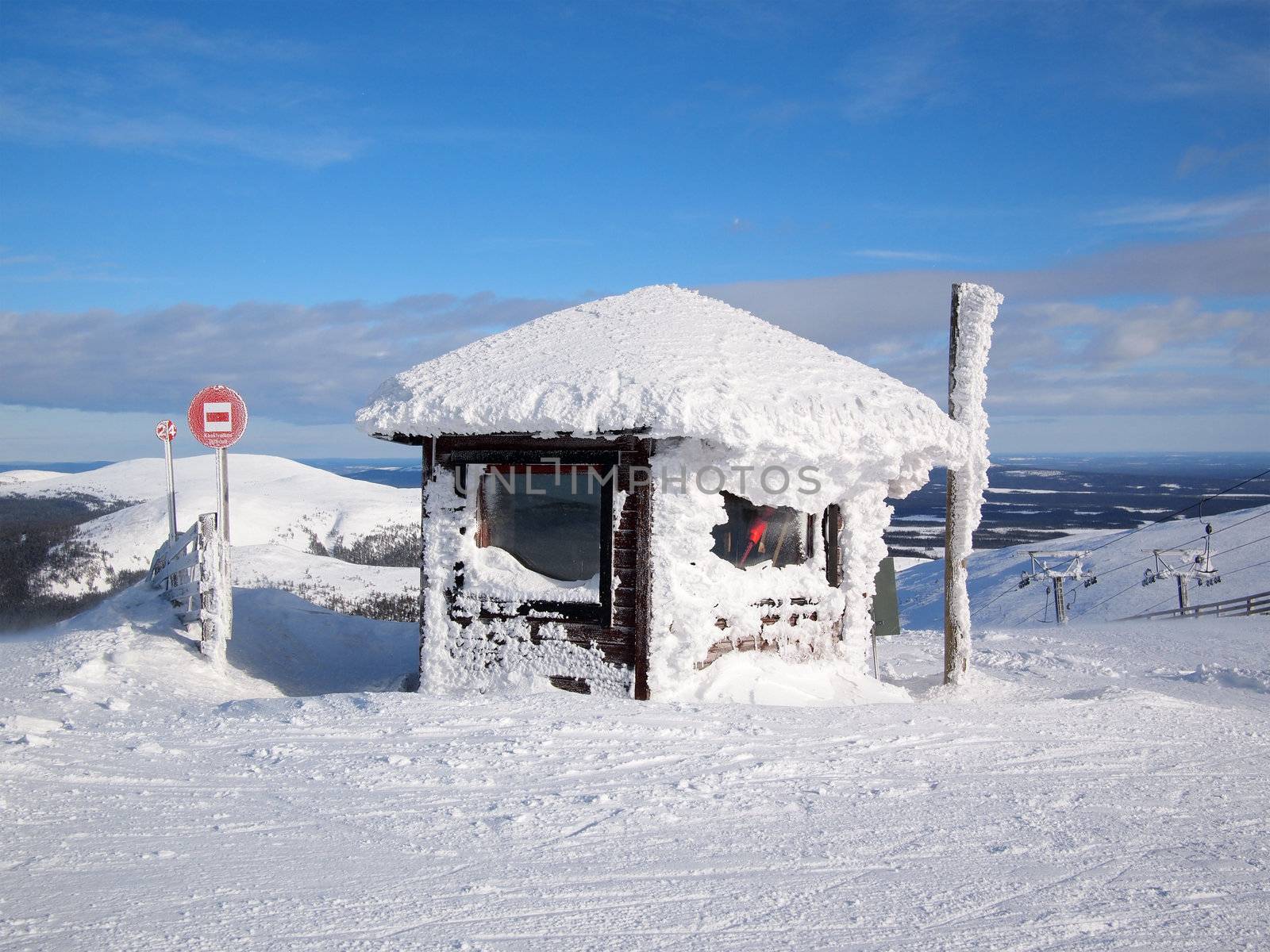 Snow covered chalet next to a ski piste sign on a mountain in the Finnish ski area of Yllas in Lapland, Finland.
