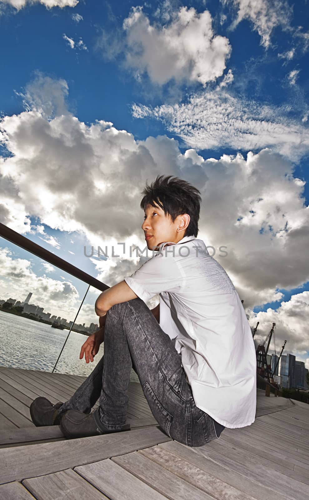 asian man sitting in park by cozyta