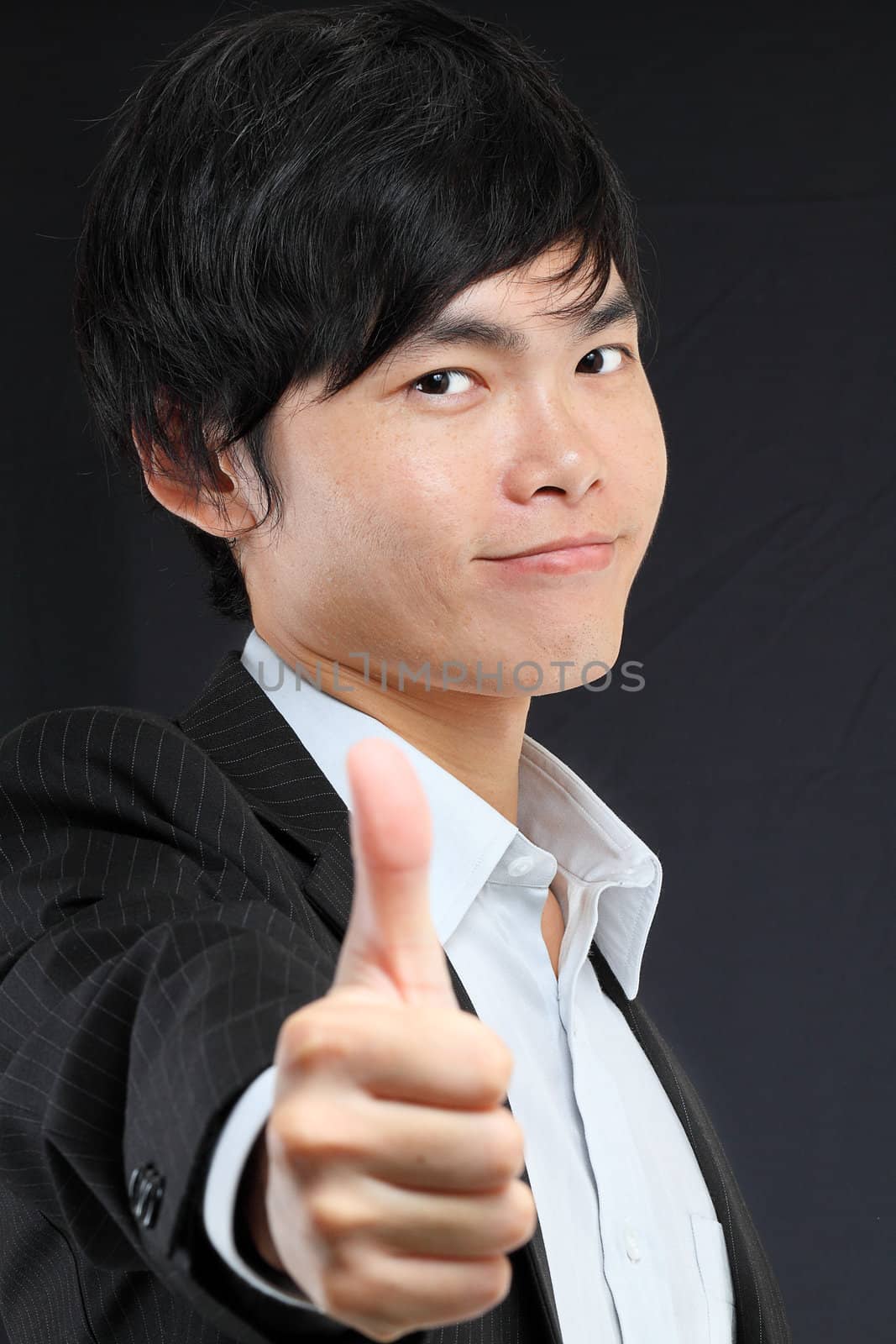 portrait of young man in suit and thumbs up by cozyta