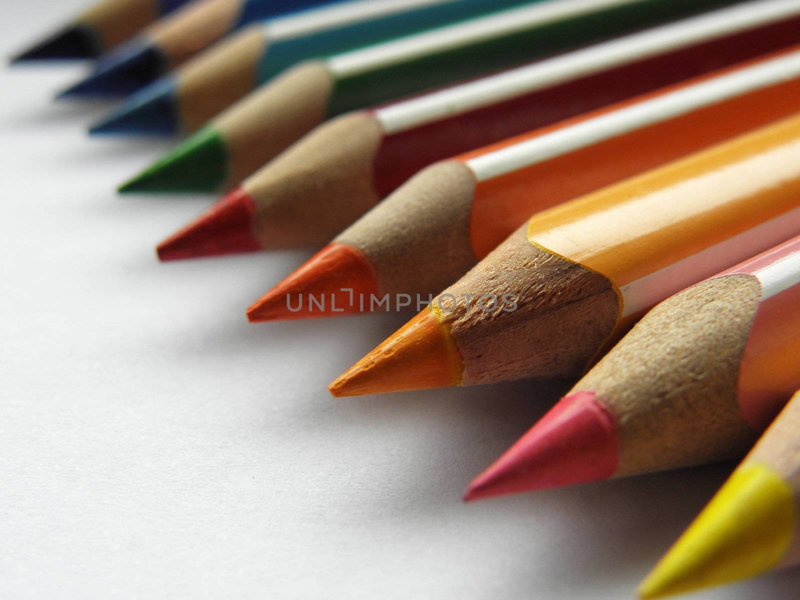 Colorful pencils lined up diagonally on a white background.