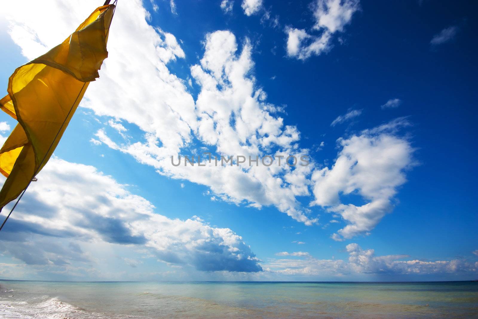 Yellow flag on a seashore with beautiful clouds background