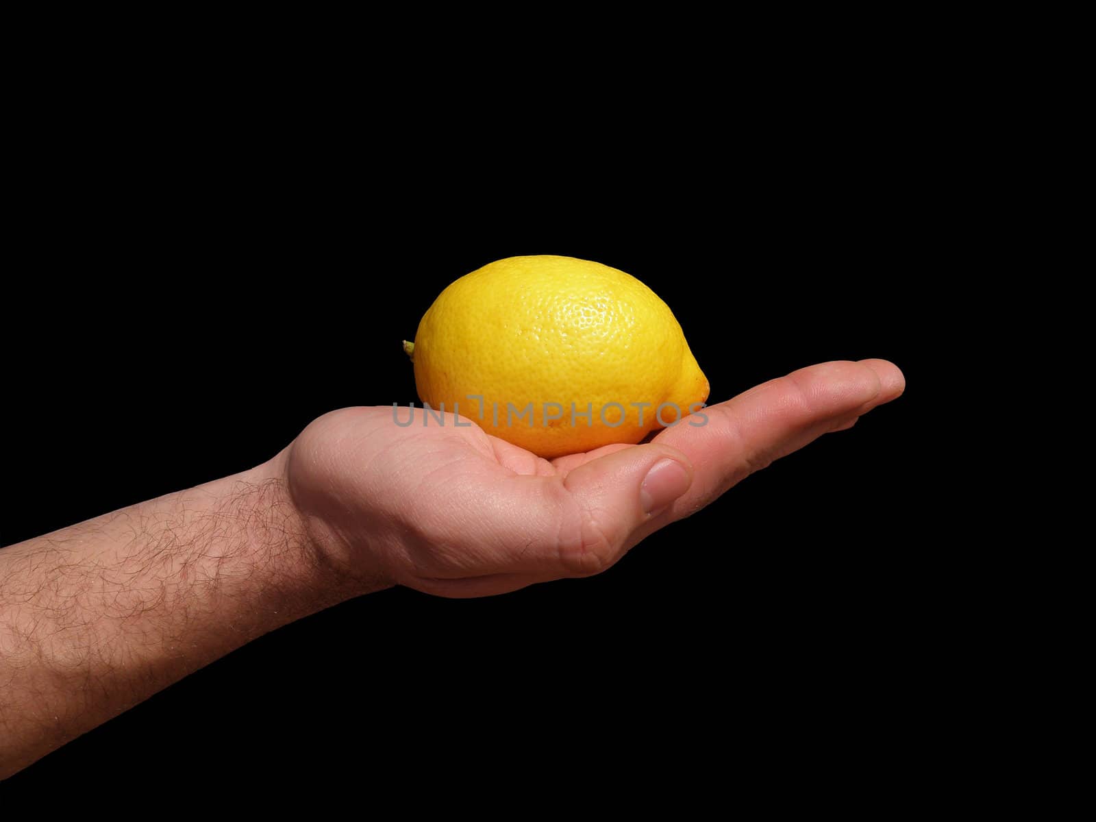 Lemon on male hand is photographed against a black background.