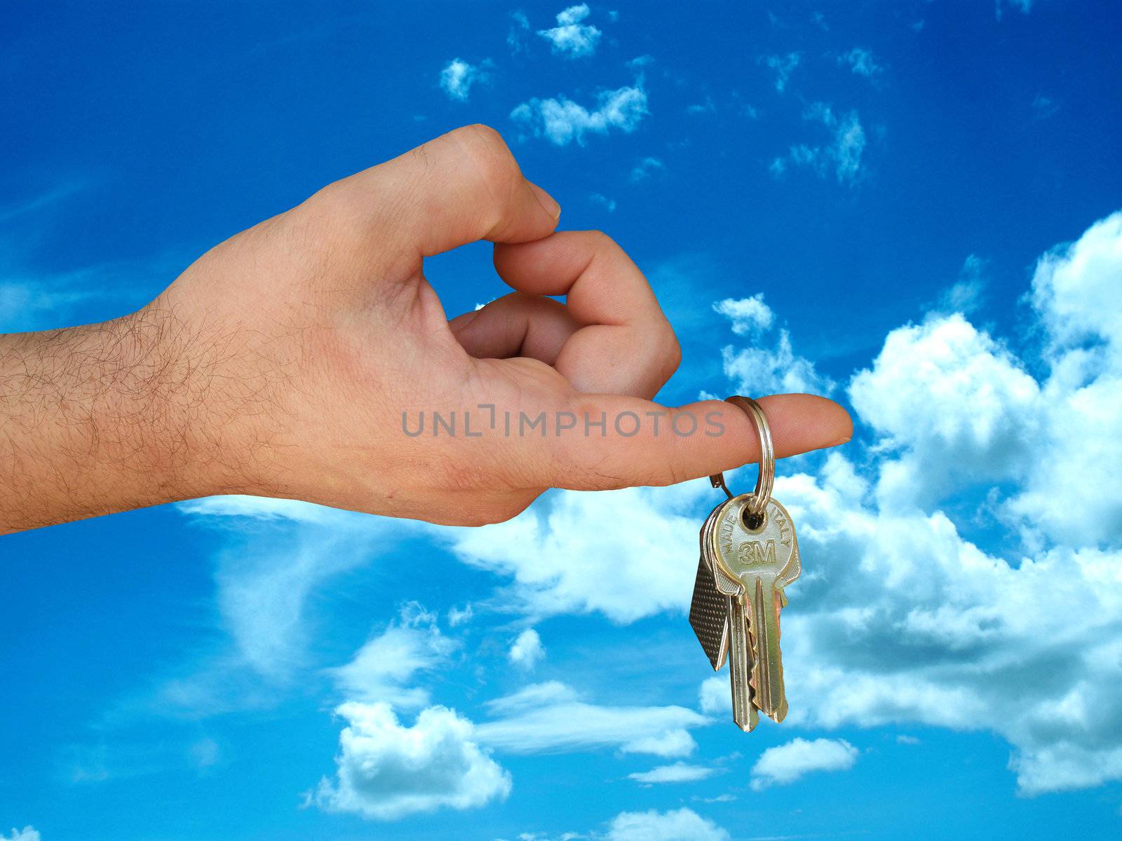 Hand photographed holding a key on the finger. With a background in the sky.