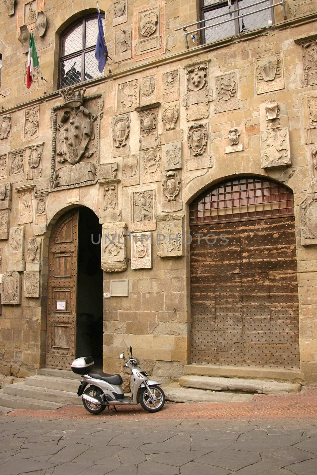 Silver scooter, antique wall, old door, stone pavement, Arezzo, Italy