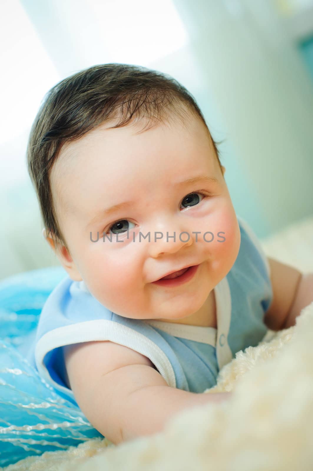 Beautiful cute baby boy is lying in a bed.