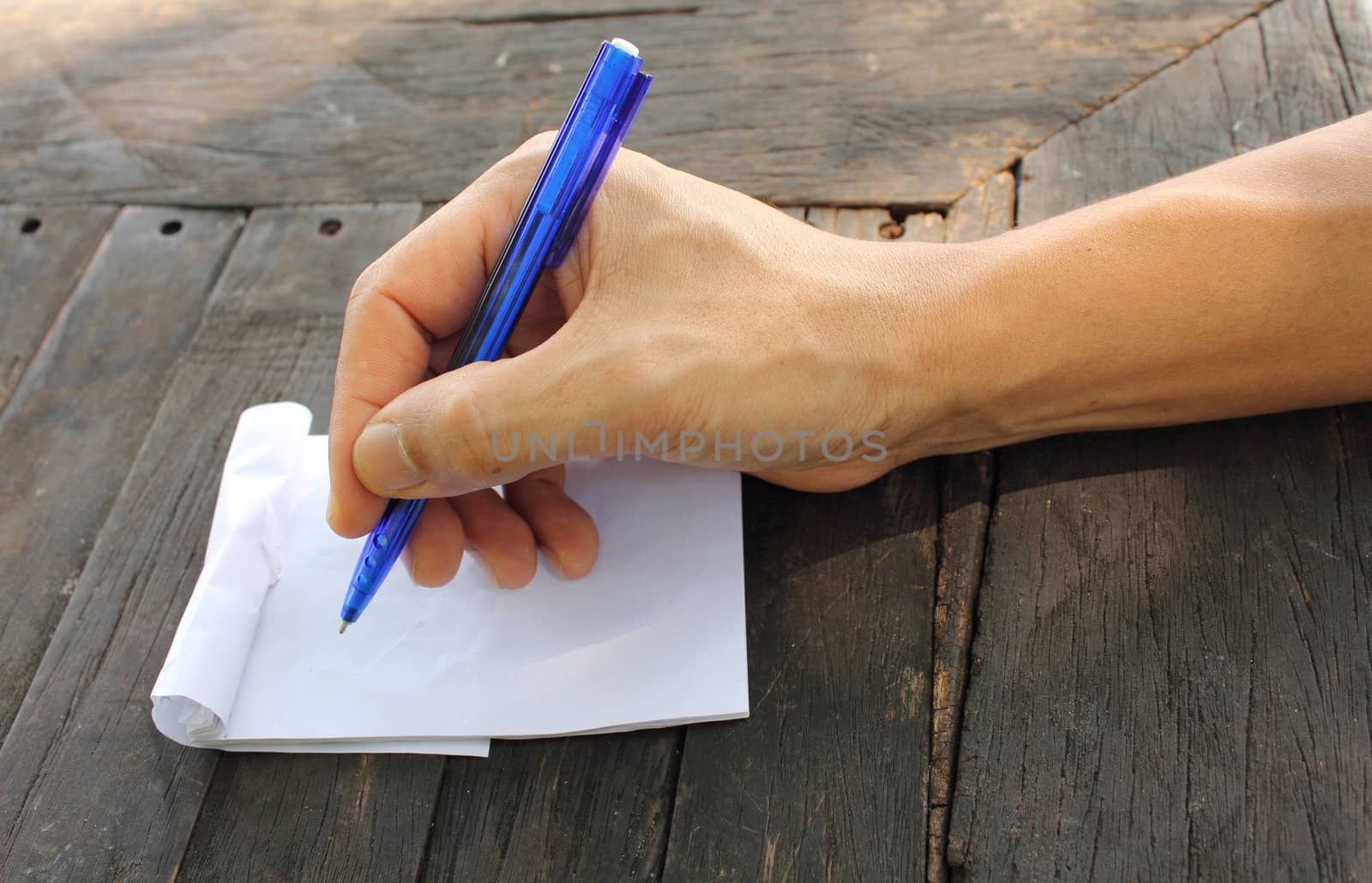 Asian male hand holding pen on an empty paper