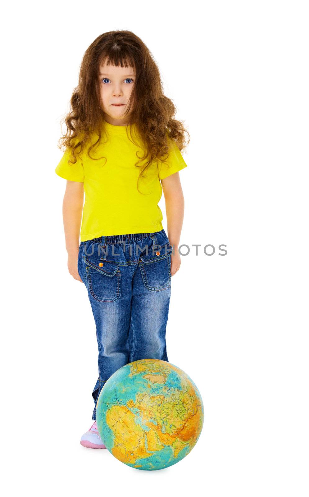 Funny little girl in jeans with a geographic globe like a soccer ball isolated on white background