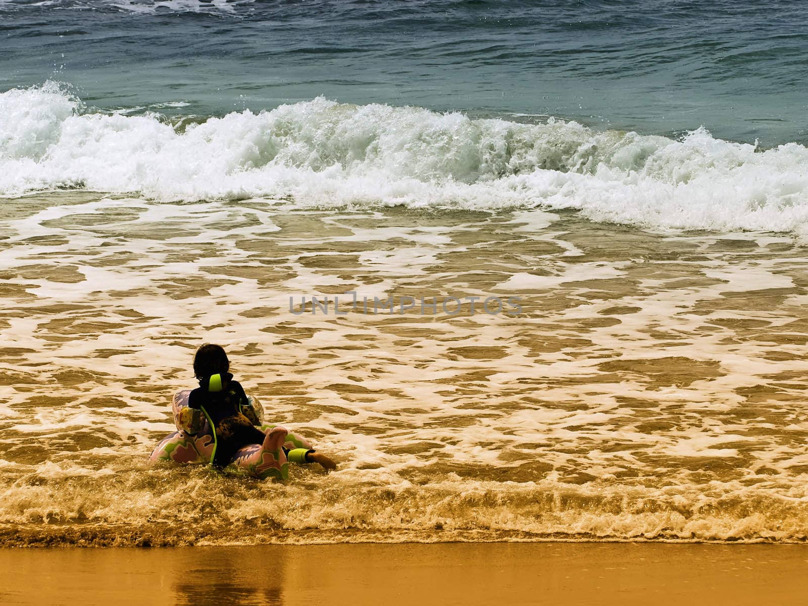 Girl playing at the water's edge on beach in Malta