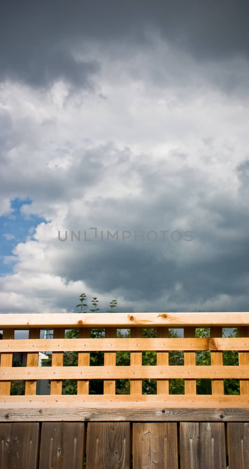 Backyard fence with lattice top under an ominous looking storm cloud.