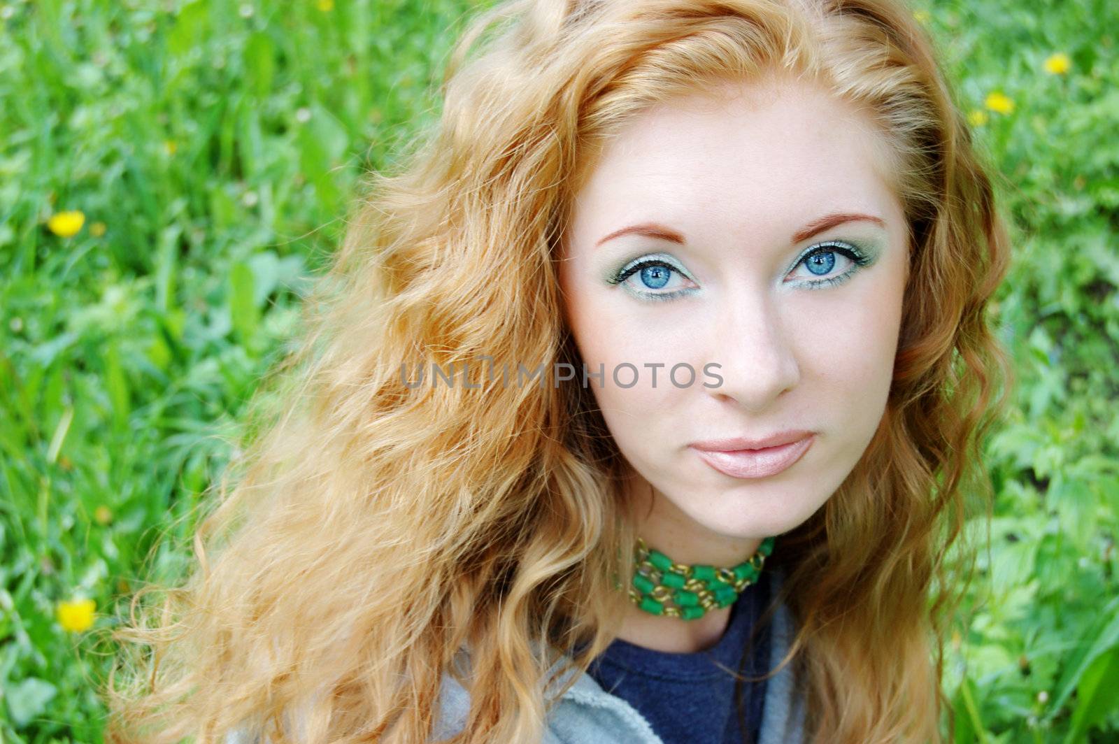 Portrait of red-hared girl over green grass