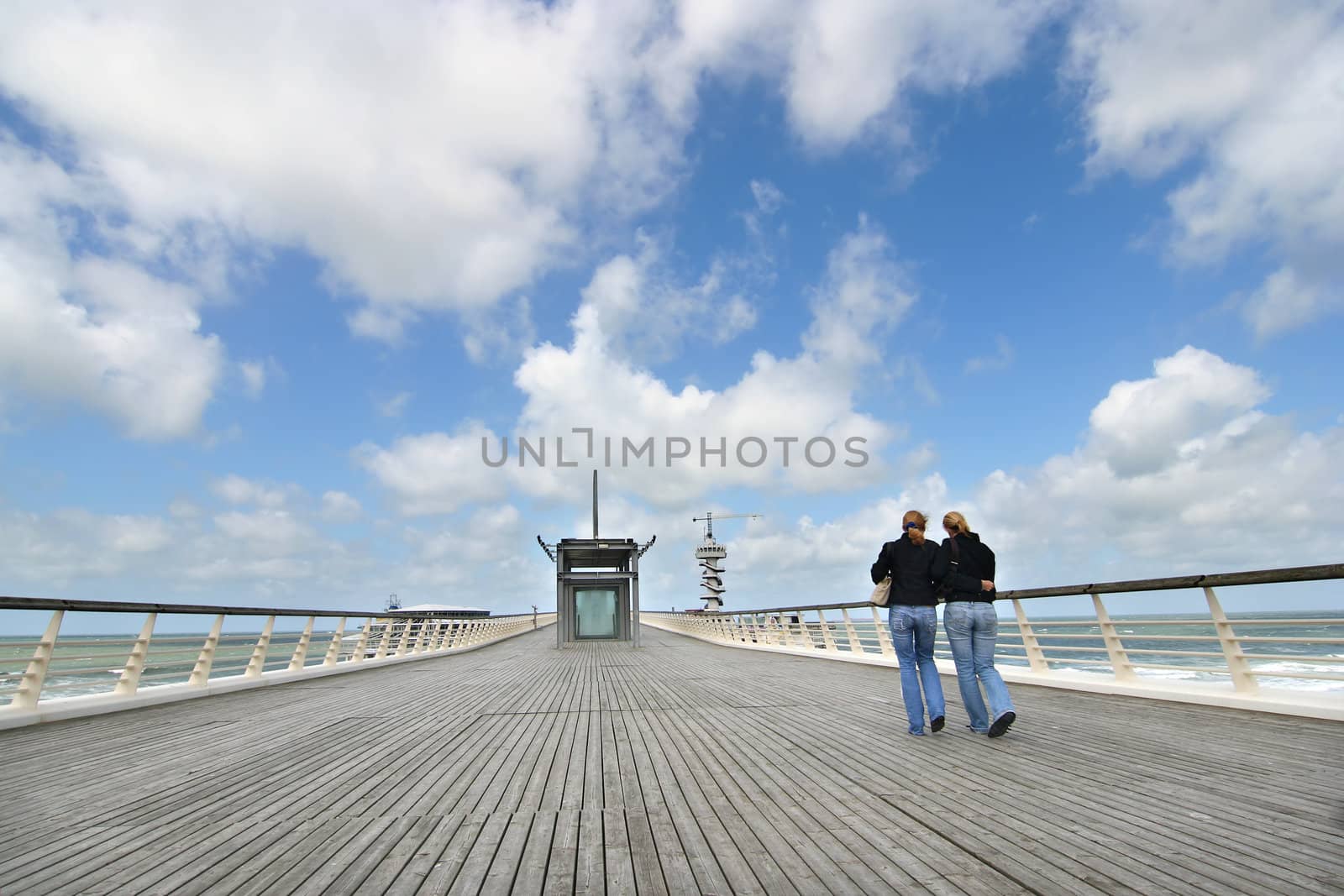 Two female friends walking on a pier