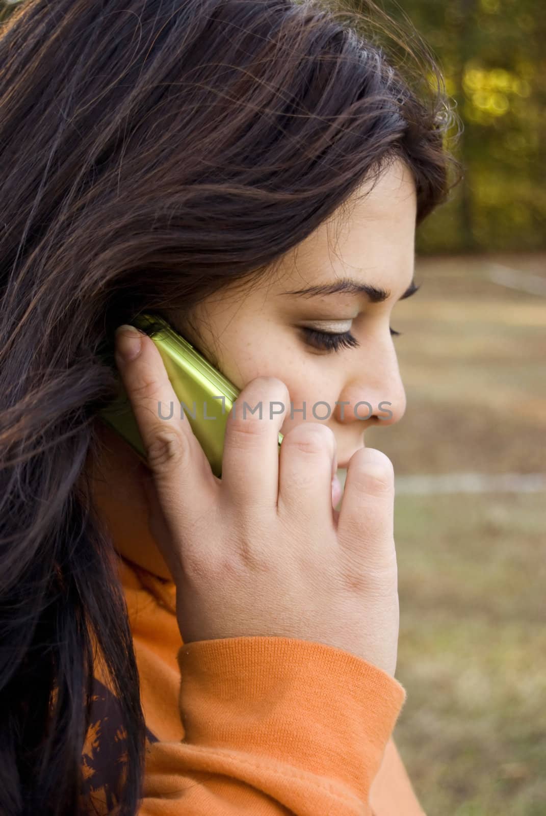 A beautiful young woman of latin descent talking on a cell phone.