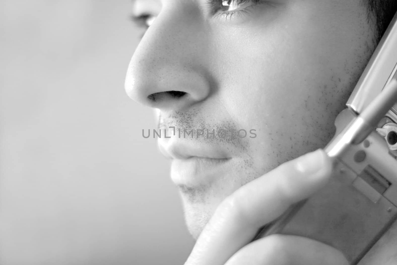 Black and white portrait of a young man on his celly phone.  He is listening with a  serious look of concern on his face.