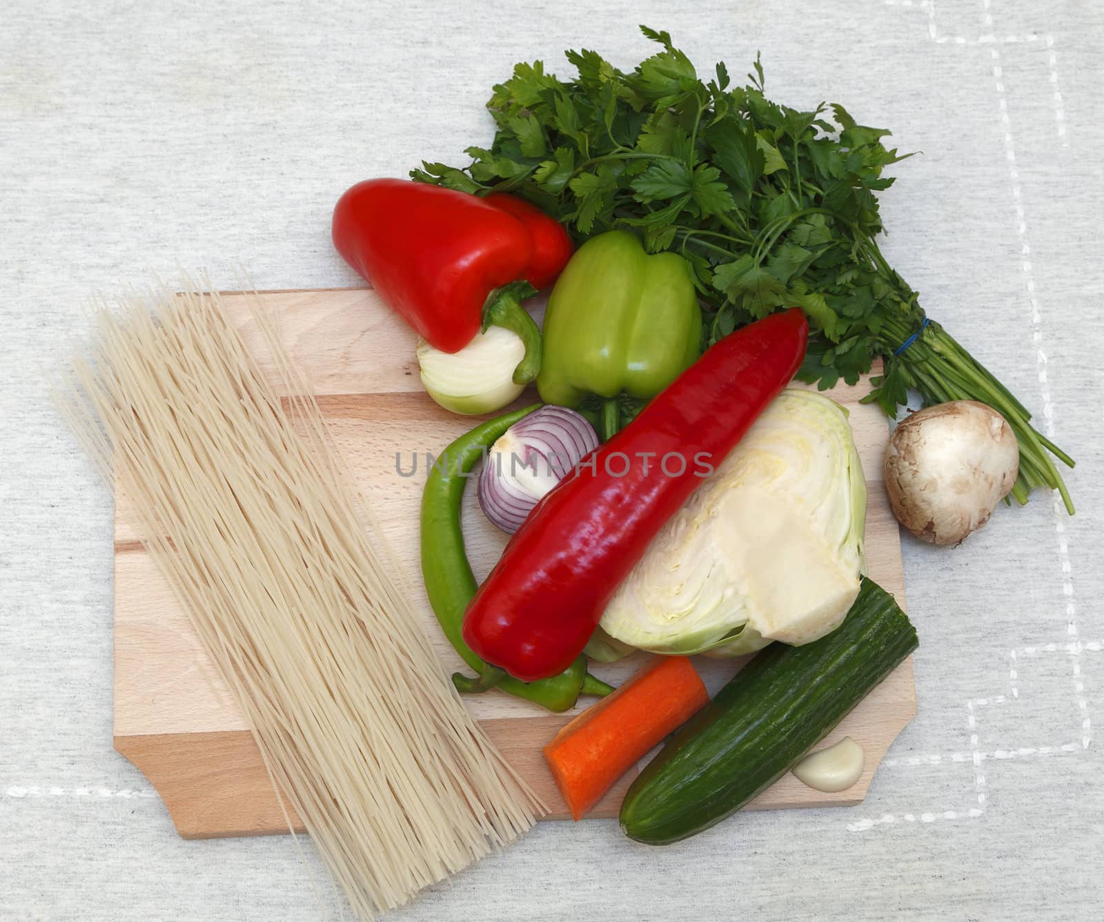 Upper view of various vegetables and pasta on a chopping board.