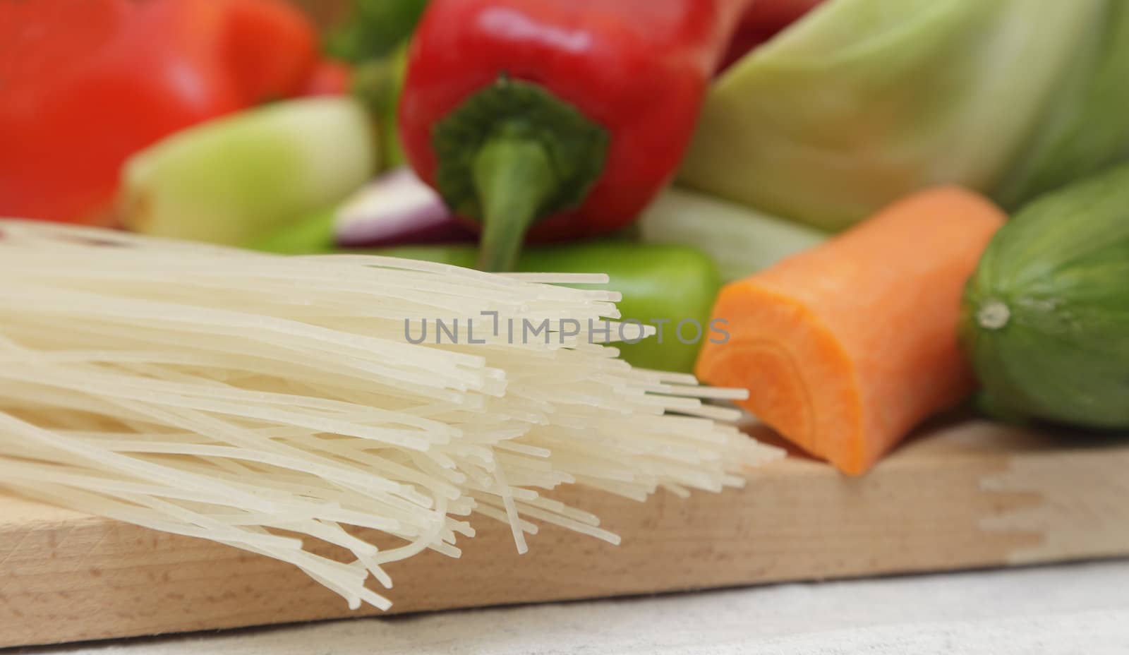 Image of pasta and various vegetables on a chopping board on a table.