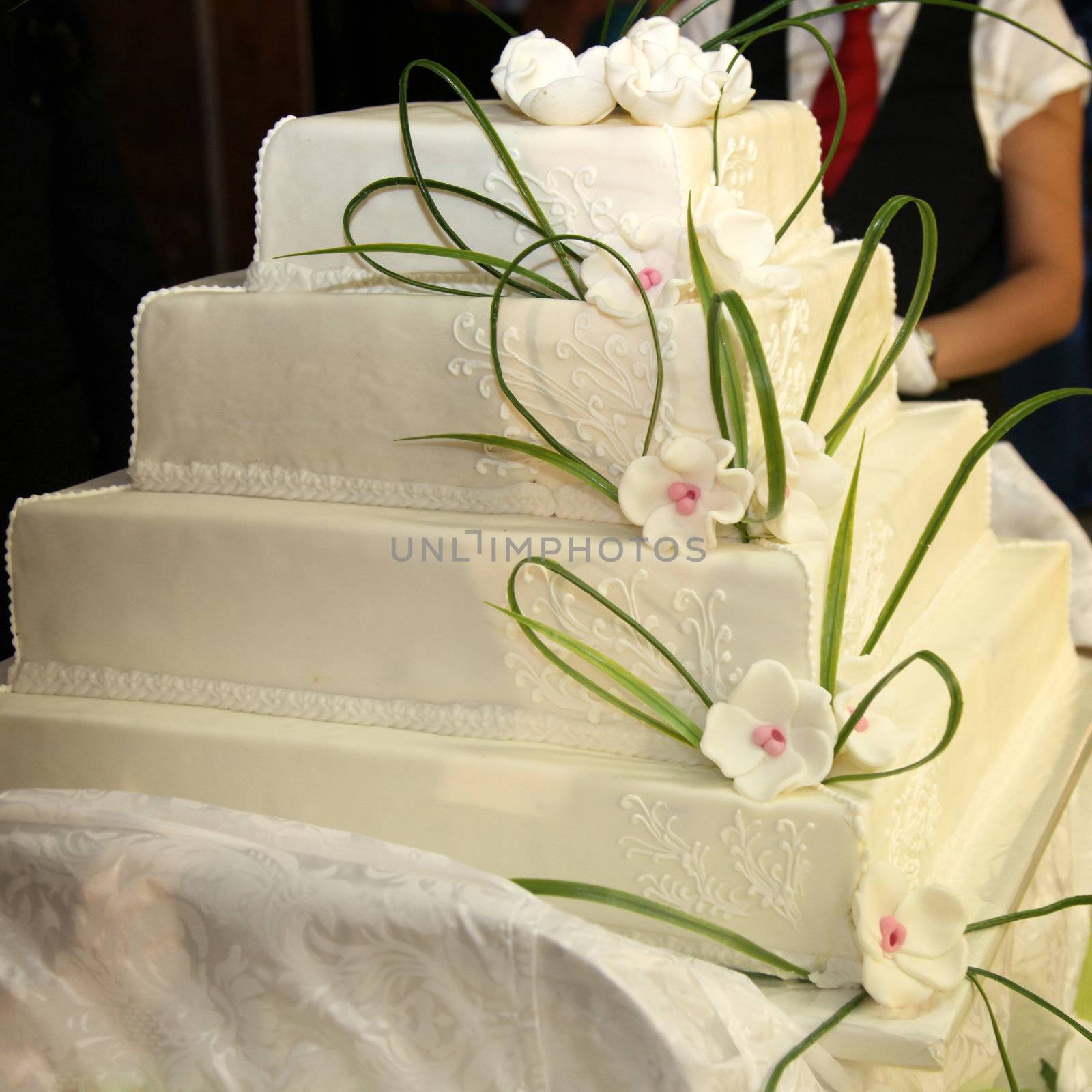Huge, four-tiered wedding cake or birthday cake with rose decoration - English style - with a waiter in the background