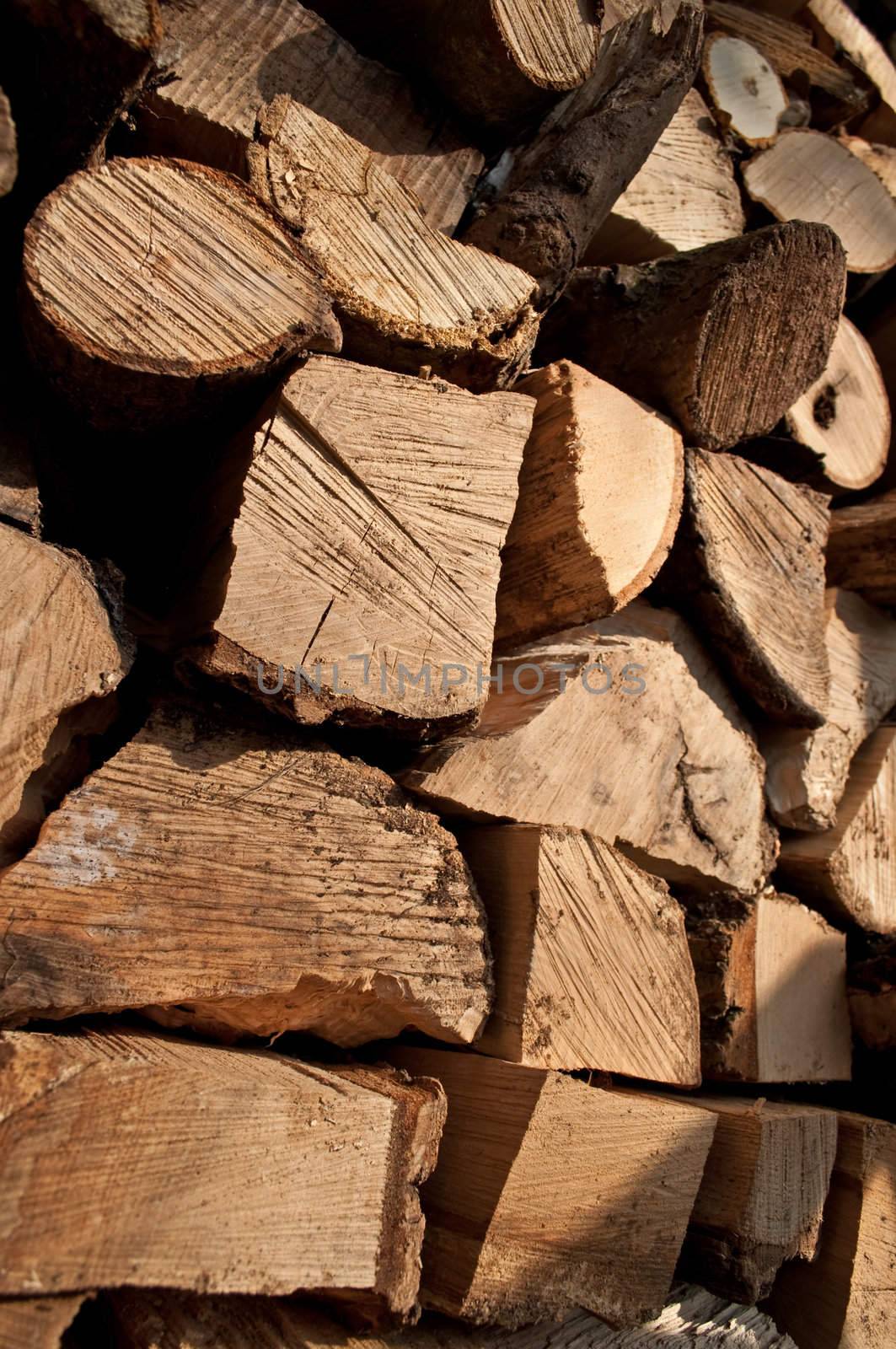 Close up on the ends of a large group of stacked, chopped rustic fire wood in outdoor setting with full sunlight