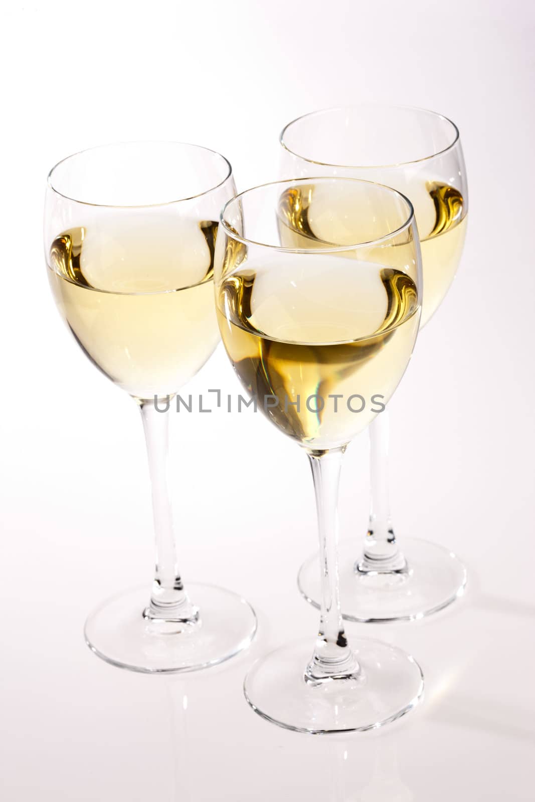 three glasses with white wine over light bsckground