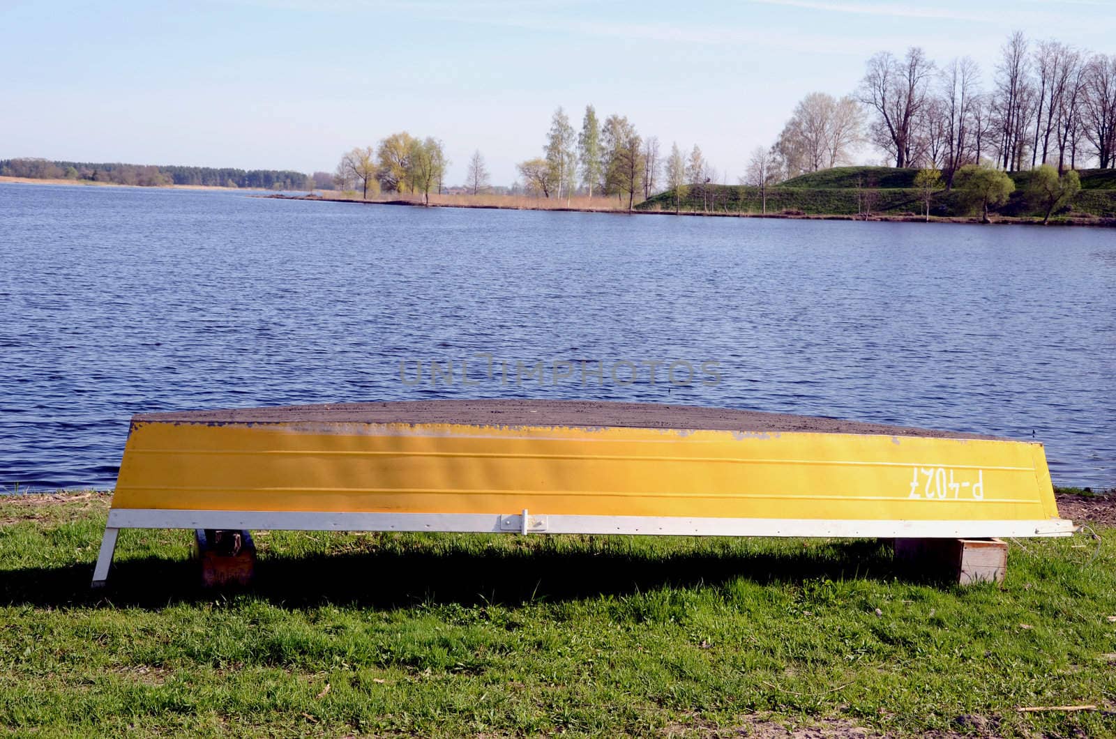 Yellow boat after winter on the coast of lake.