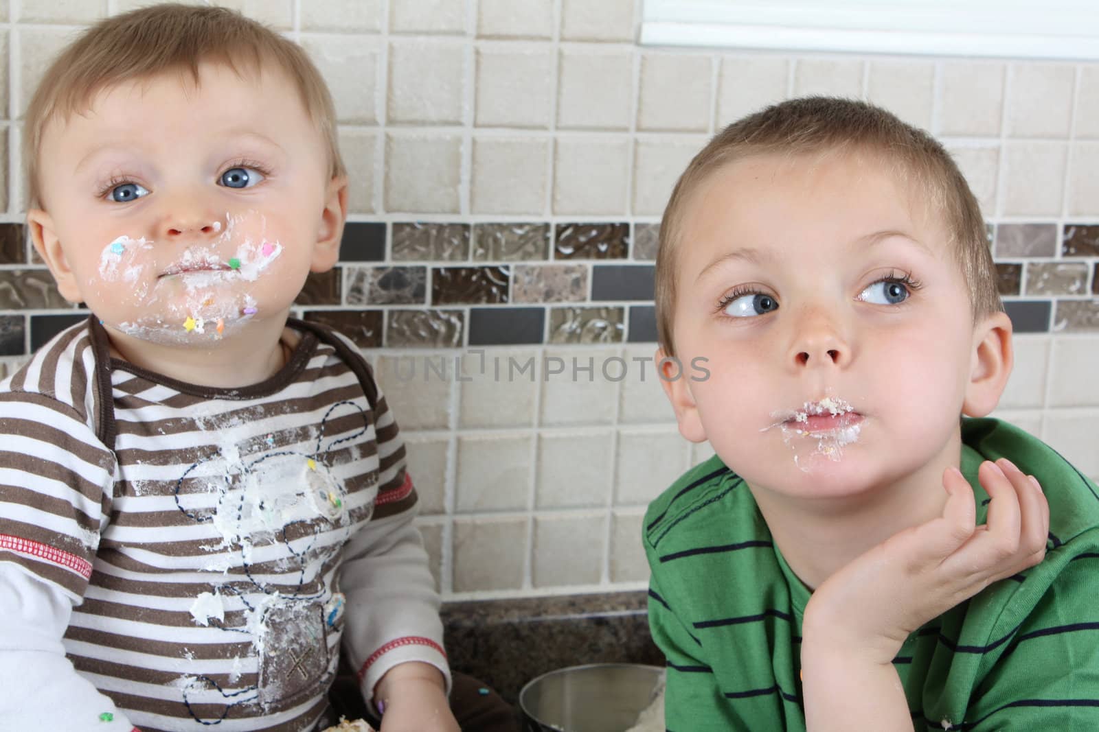 Brothers on kitchen counter eating icing sugar