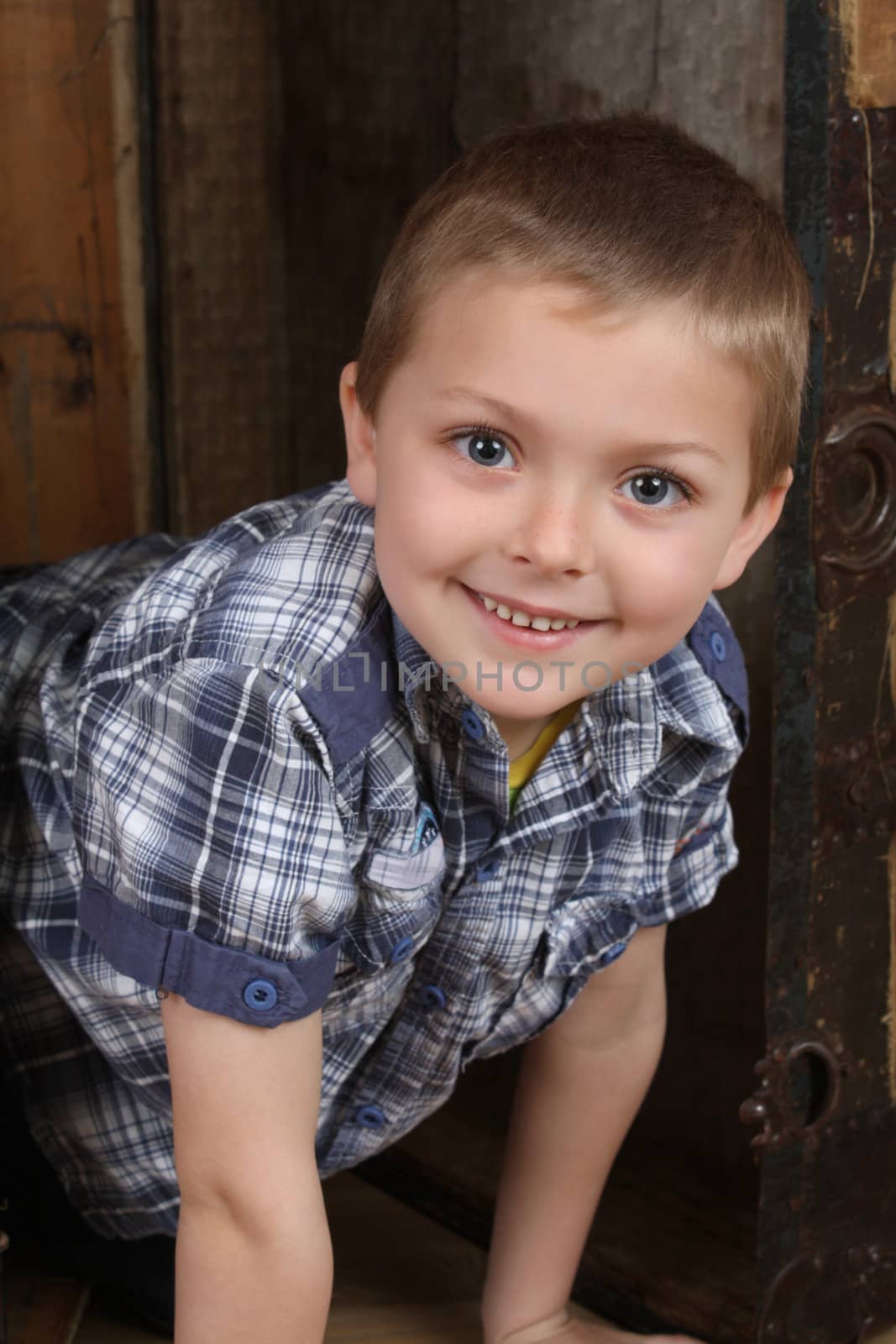 Beautiful blond boy looking out of an antique trunk