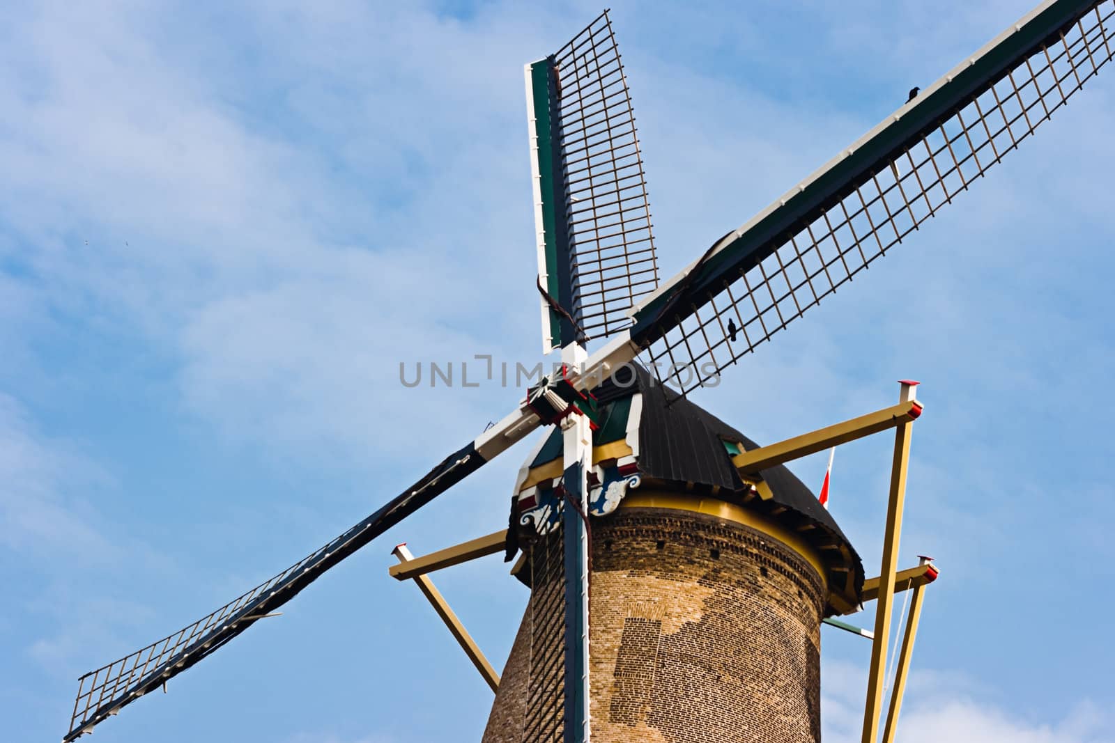 Blades of historic Dutch windmill still in use to grind corn with blue sky background