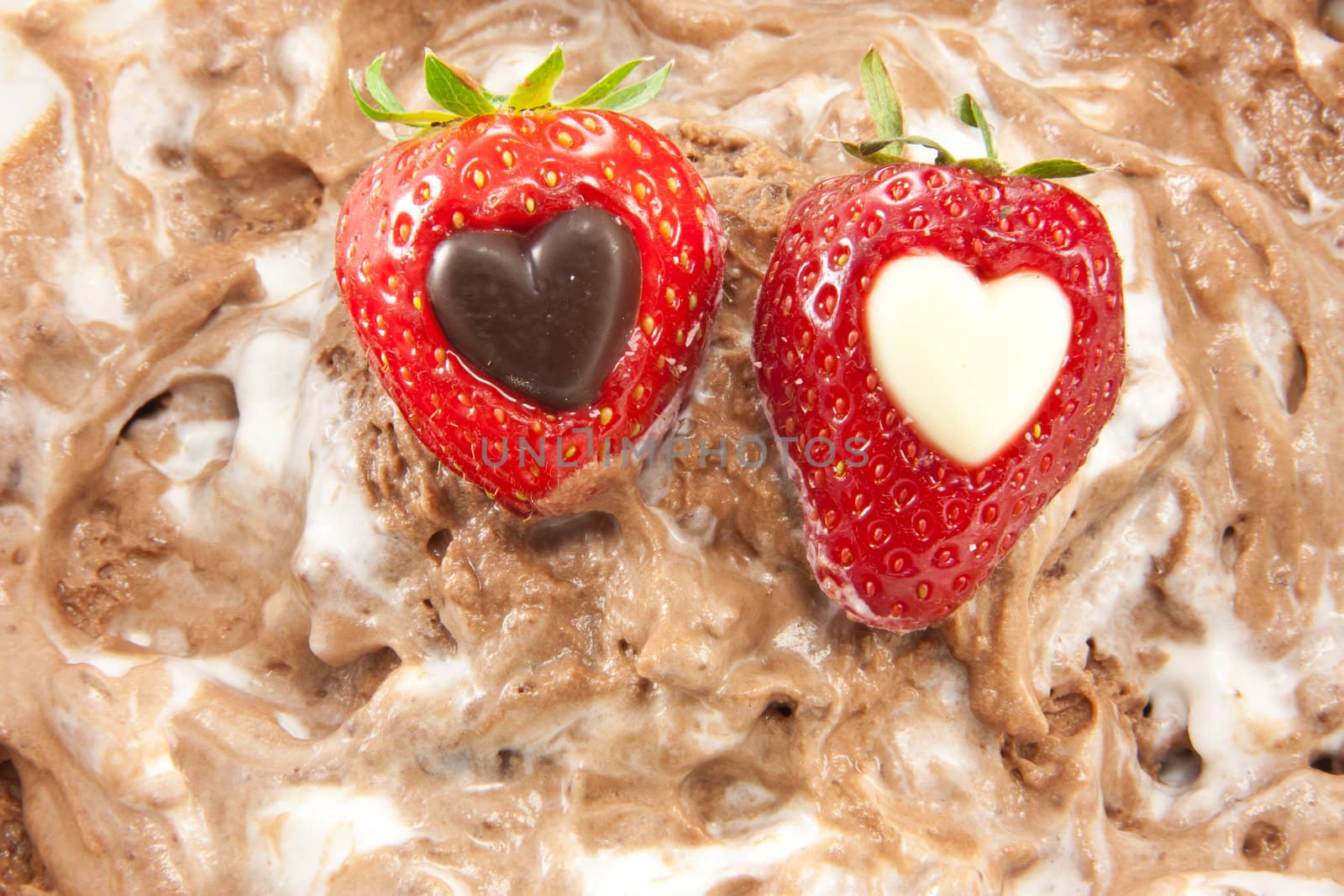 Picture of two strawberries with a heart center laying on mixed up chocolate mousse