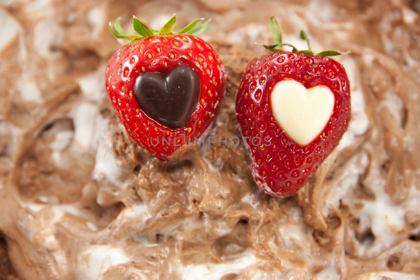 Picture of two strawberries with a heart center laying on mixed up chocolate mousse