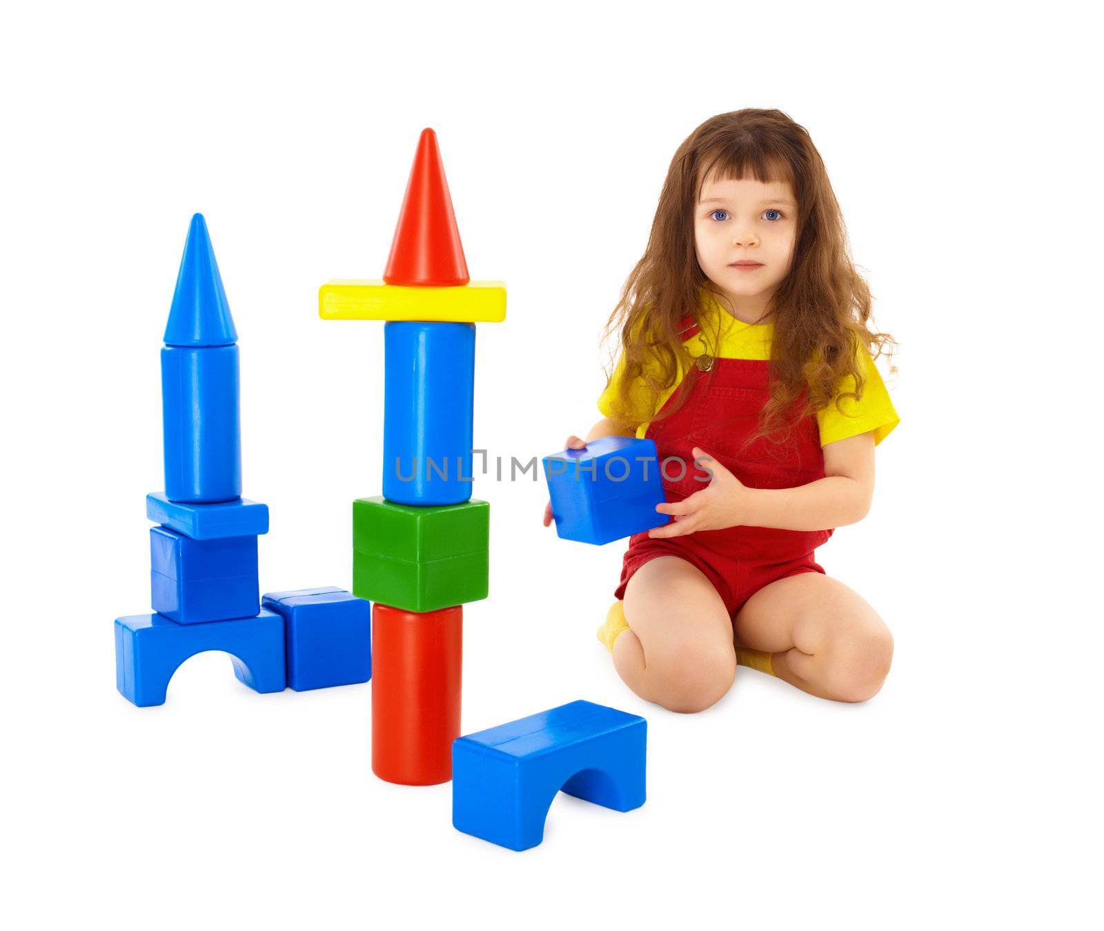 The child builds a toy castle on the floor isolated on white background