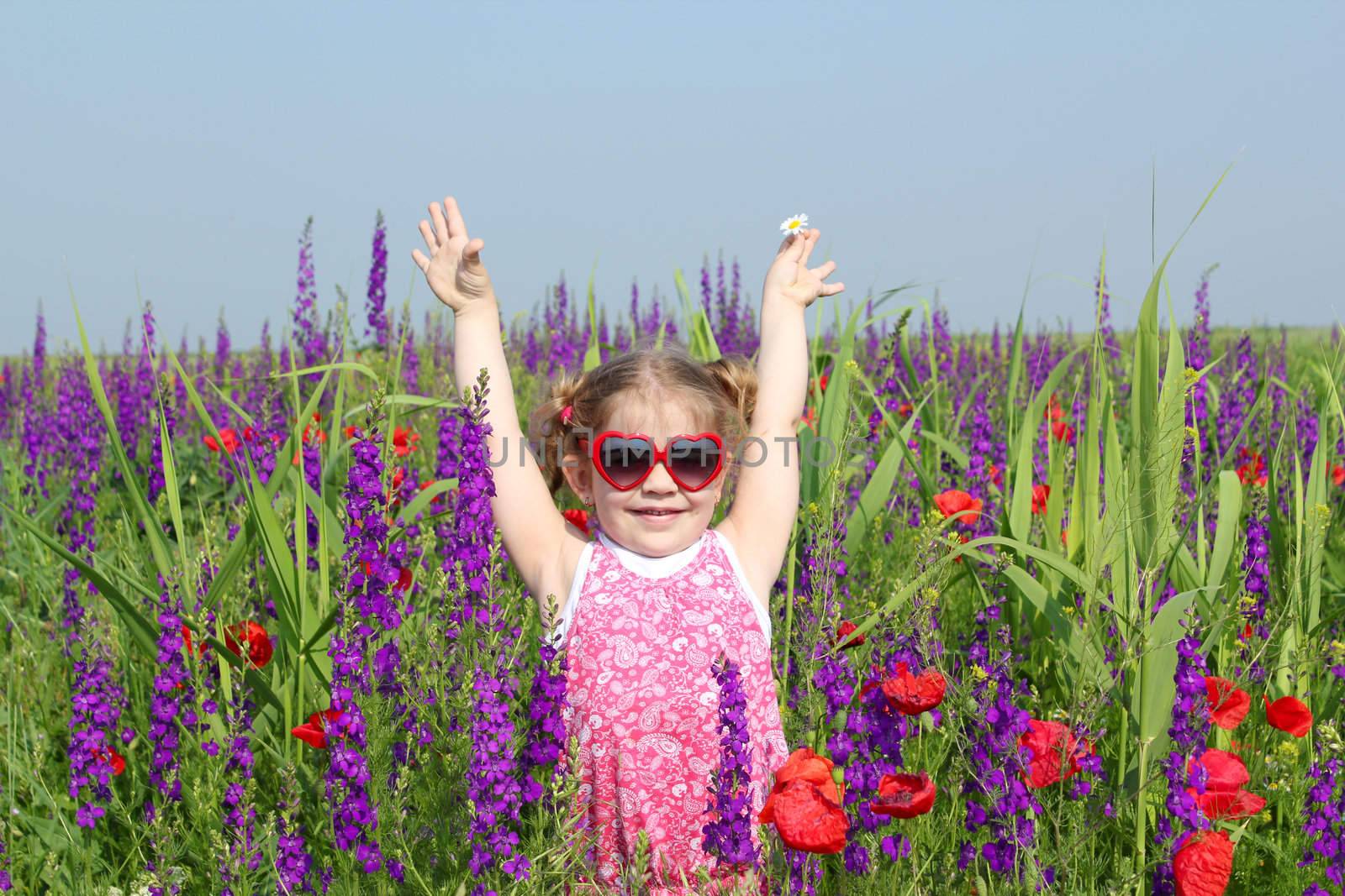 happy little girl standing in colorful meadow by goce