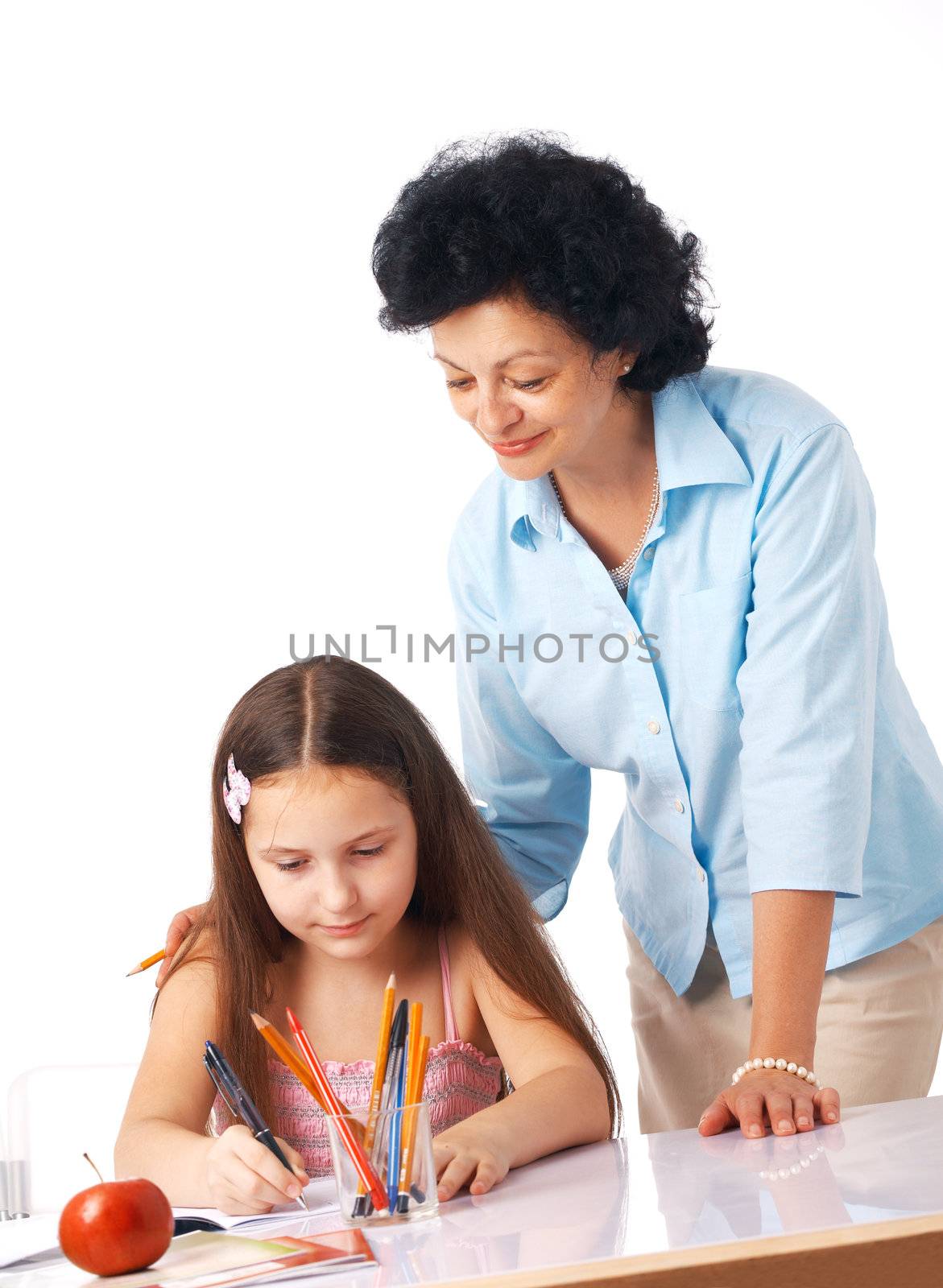 Grandmother standing over her granddaughter and helping her with home-work.