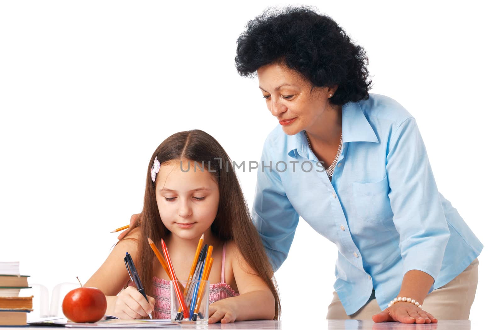 Grandmother standing over her granddaughter and helping her with home-work.