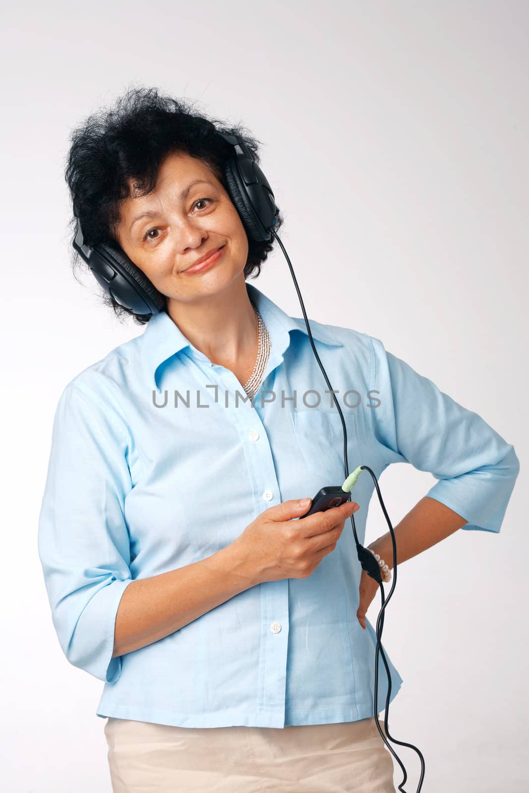 Elder happy woman with phones and mobile listening something.