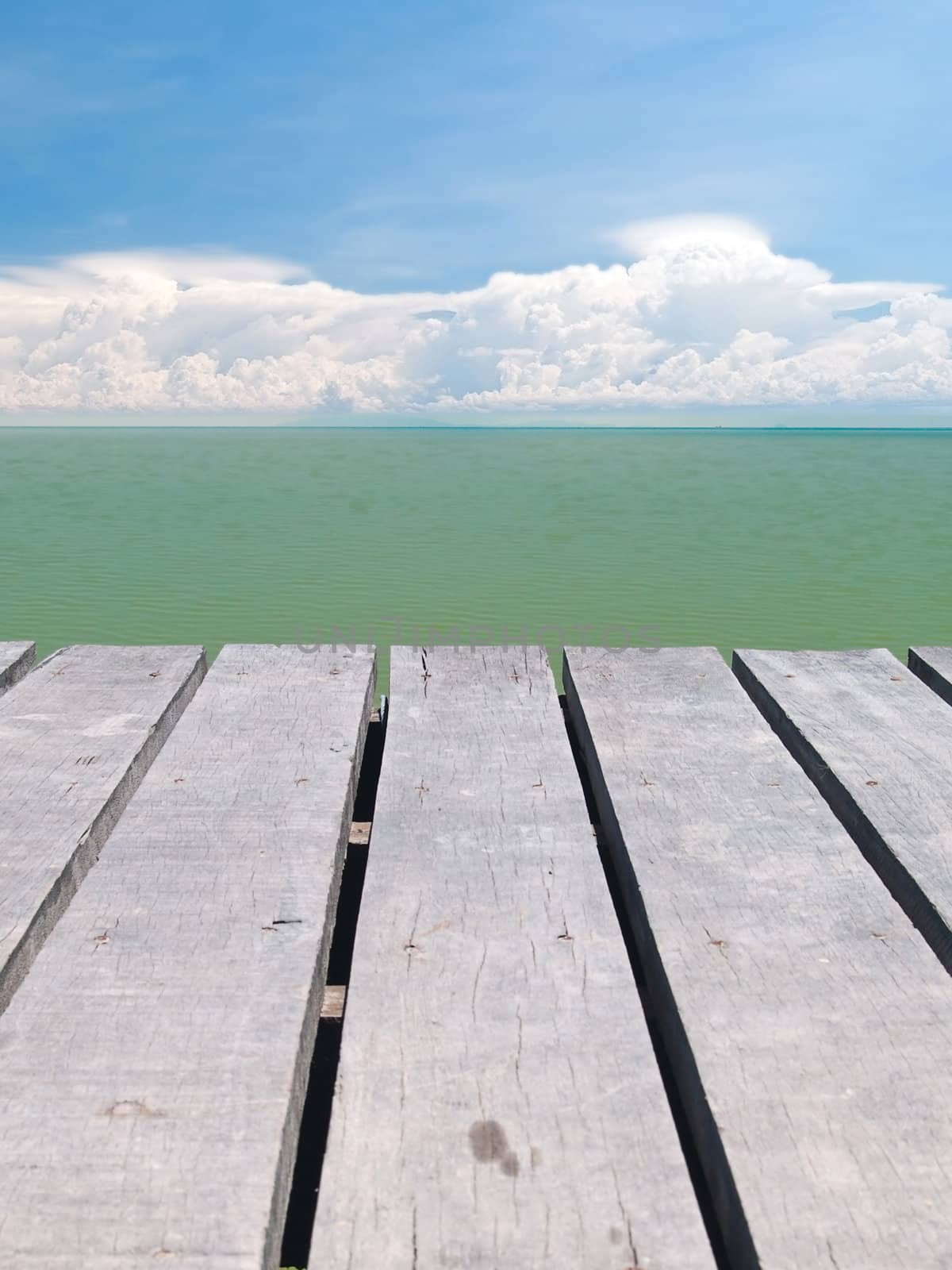 Seaside wooden bridge with beautiful cloudy and emerald color backwater sea