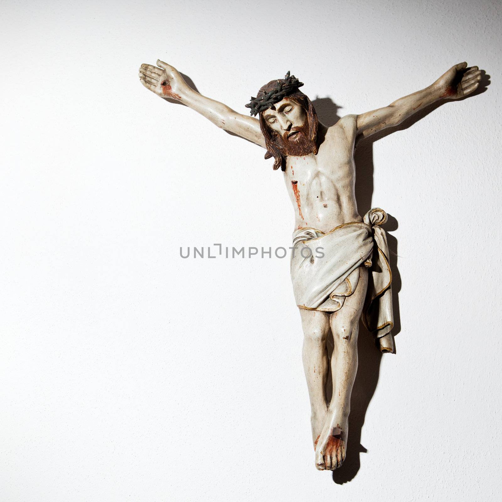 Very old carved and painted wooden crucifix on a wall in a historical country cottage