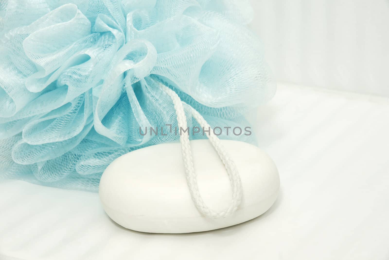 Blue shower puff and soap on tiles by Mirage3